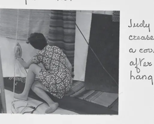 "Judy takes a crease out of a coverlet after it is hanging up."
