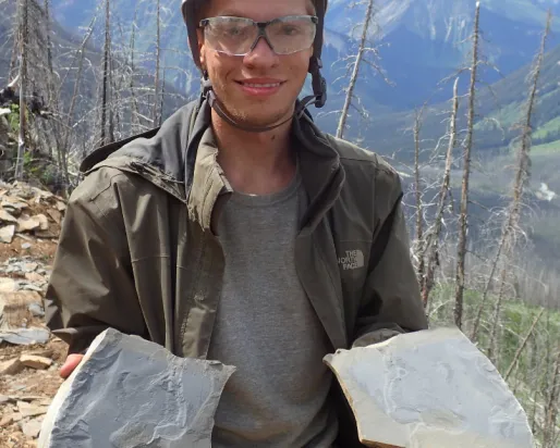 Student holding shale slabs with fossils.
