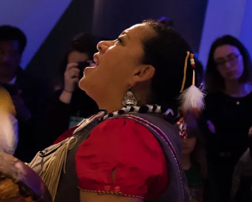 Kim Wheatley drums and sings an Anishnaabe blessing to the skeleton of the blue whale. Photo by Rachel Brown
