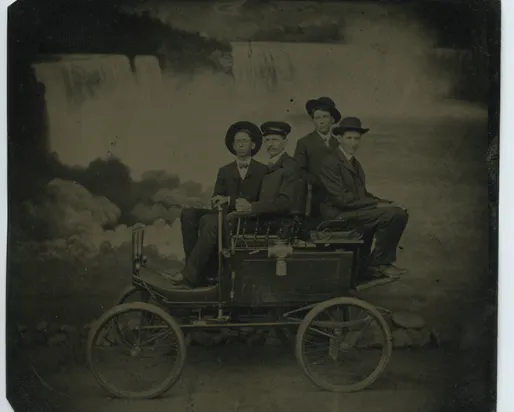 Photo de ferrotype noir et blanc de quatre hommes assis sur un chariot devant les chutes du Niagara
