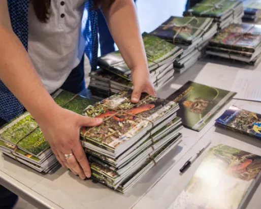 Un bénévole rassemble une pile de livres de la Toronto Biodiversity Series sur une table.
