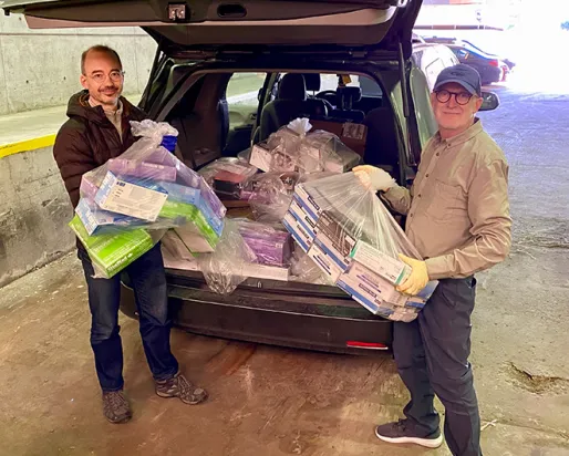 Two ROM staff load an SUV with PPE.