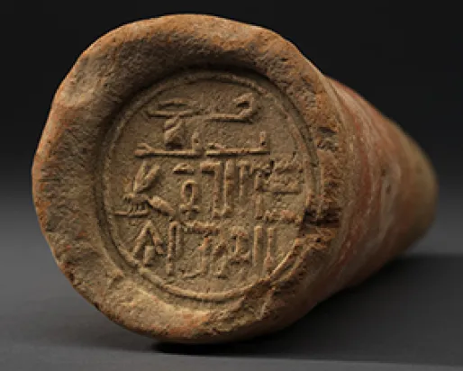 A clay cone with Egyptian hieroglyphs stamped on the flat face.