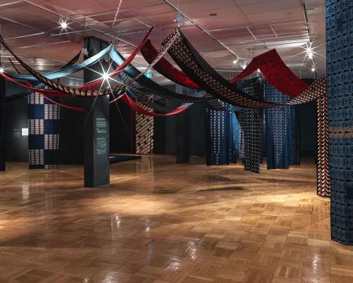 Panoramic view of a soft sculpture installation consisting of lengths of printed cotton fabric suspended from above.