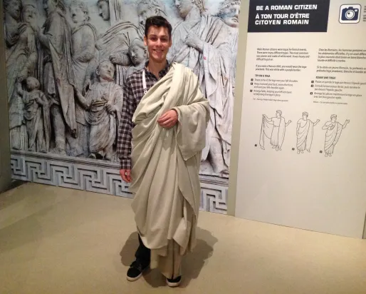 A young man wears a white toga
