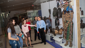 Photo of students and a teacher examining a case of objects from Africa