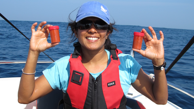 Asha de Vos, P.h.D. holds two bottles of freshly collected blue whale poop off the coast of Sri Lanka. Photo Credit: Oceanswell