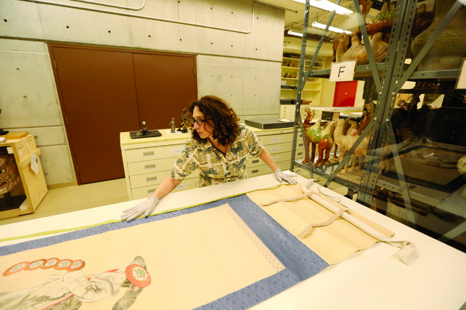 A woman measuring an ancient Japanese print