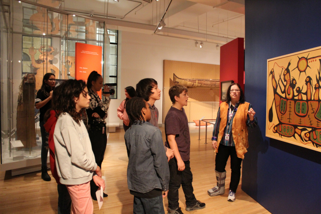 A teacher explaining a painting to students in the First Peoples Gallery