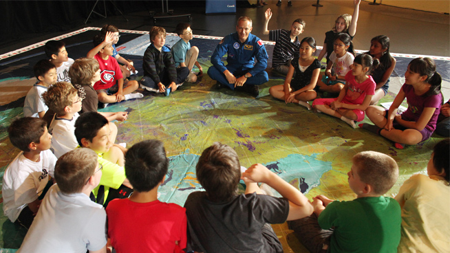 In this photo, taken in 2014, Canadian Space Agency (CSA) astronaut David Saint-Jacques unveiled the Canada from Space Giant Floor Map to a group of students in Ottawa. © Canadian Space Agency.