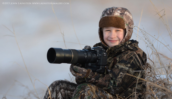 Ten-year-old wildlife photographer Josiah Launstein sits bundled up and ready to take the shot.