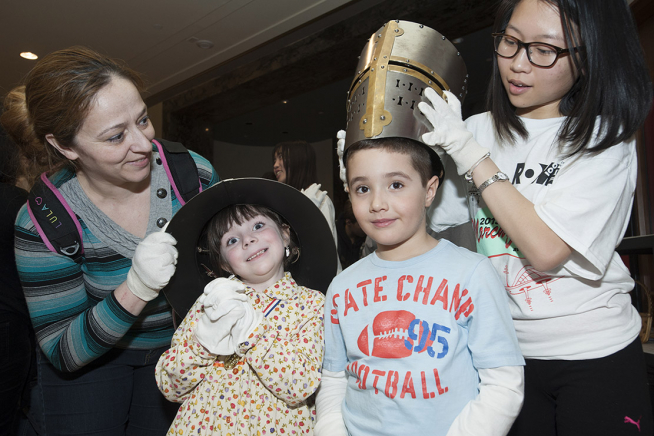 ROM Volunteer helps children try on armour during March Break 2015