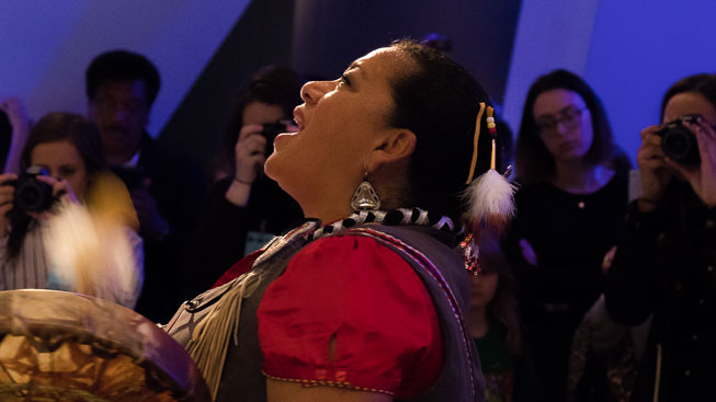 Kim Wheatley drums and sings an Anishnaabe blessing to the skeleton of the blue whale. Photo by Rachel Brown