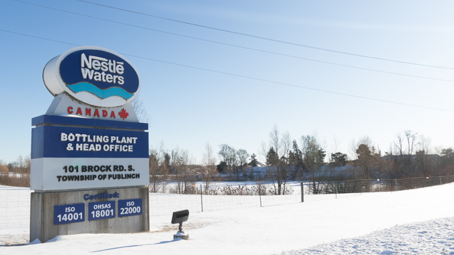Large sign in snowy field reads: Nestlé Waters Canada bottling plant and head office 101 Brock Rd.S., Township of Puslinch
