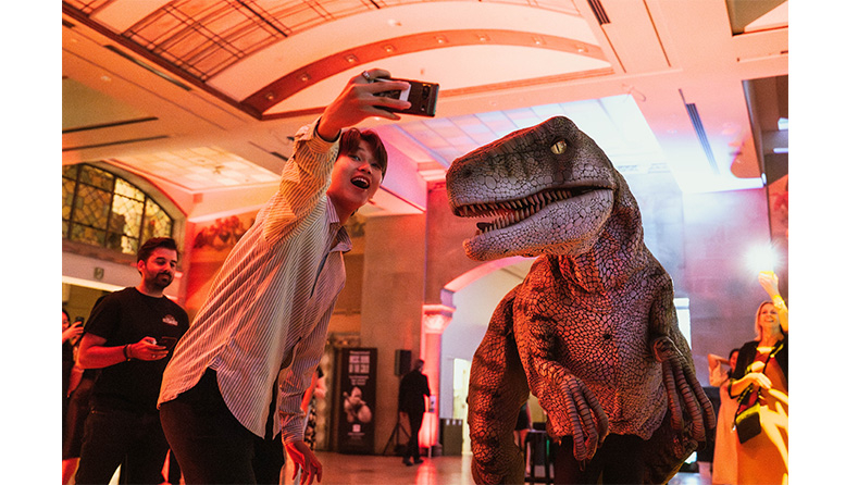 A boy taking a picture with a velociraptor statue at Royal Ontario Museum. 