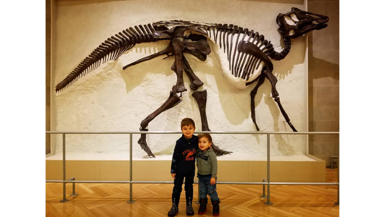 Brother posing for photo in front of dinosaur skeleton 