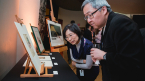 A man and a woman look intently at Japanese art 