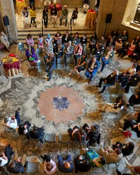 Presentation attendees in a large circle listening to a presentation.