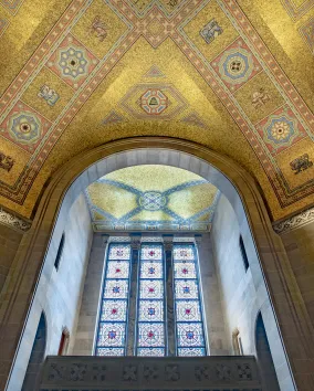 The ceiling of the ROM Rotunda the gold tiles shimmer in the light coming through the stain glass window.