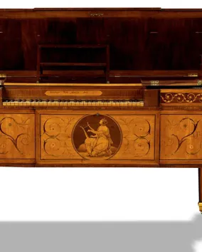 An ornate, antique wooden piano with decorative inlays, gold accents, and an image of a seated woman playing a lyre on the front panel, displayed against a white background.