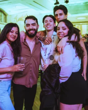 A group of people posing in a crowd with a green lighting in the background.