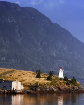 A lighthouse with a mountain in the background.