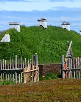 A dwelling with a grass-topped roof, surrounded by a fence.