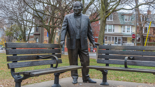 Statue of Al Waxman, between two benches in park