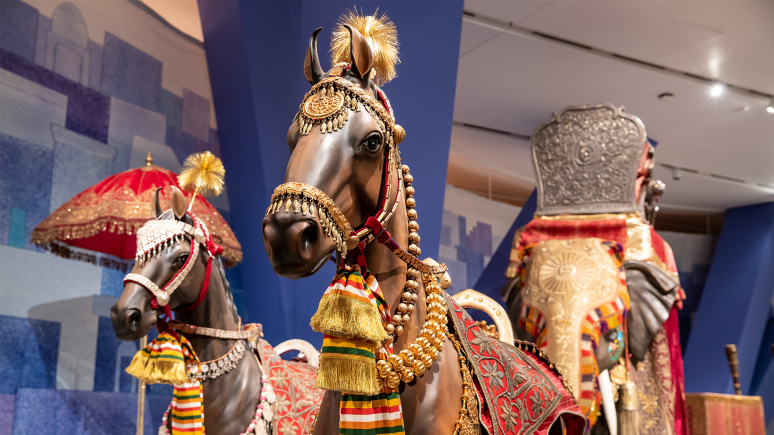 Decorated horses with saddle covers, necklaces, and tassels lead an elephant with a seat for carrying the groom.