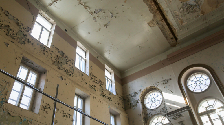 Image of a building's deteriorating interior wall and ceiling.
