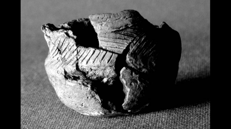 Black and white photo of broken pot that has been reassembled to show the shape and detail.