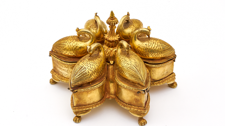 Un coffret doré à six compartiments disposés comme les pétales d'une fleur et ornés de paons recroquevillés sur eux-mêmes.