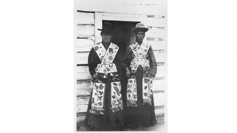 Two Anishinaabeg women wearing hats and friendship bags.