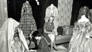 Black and white photo of Dorothy Burnham mounting a costume in the museum.