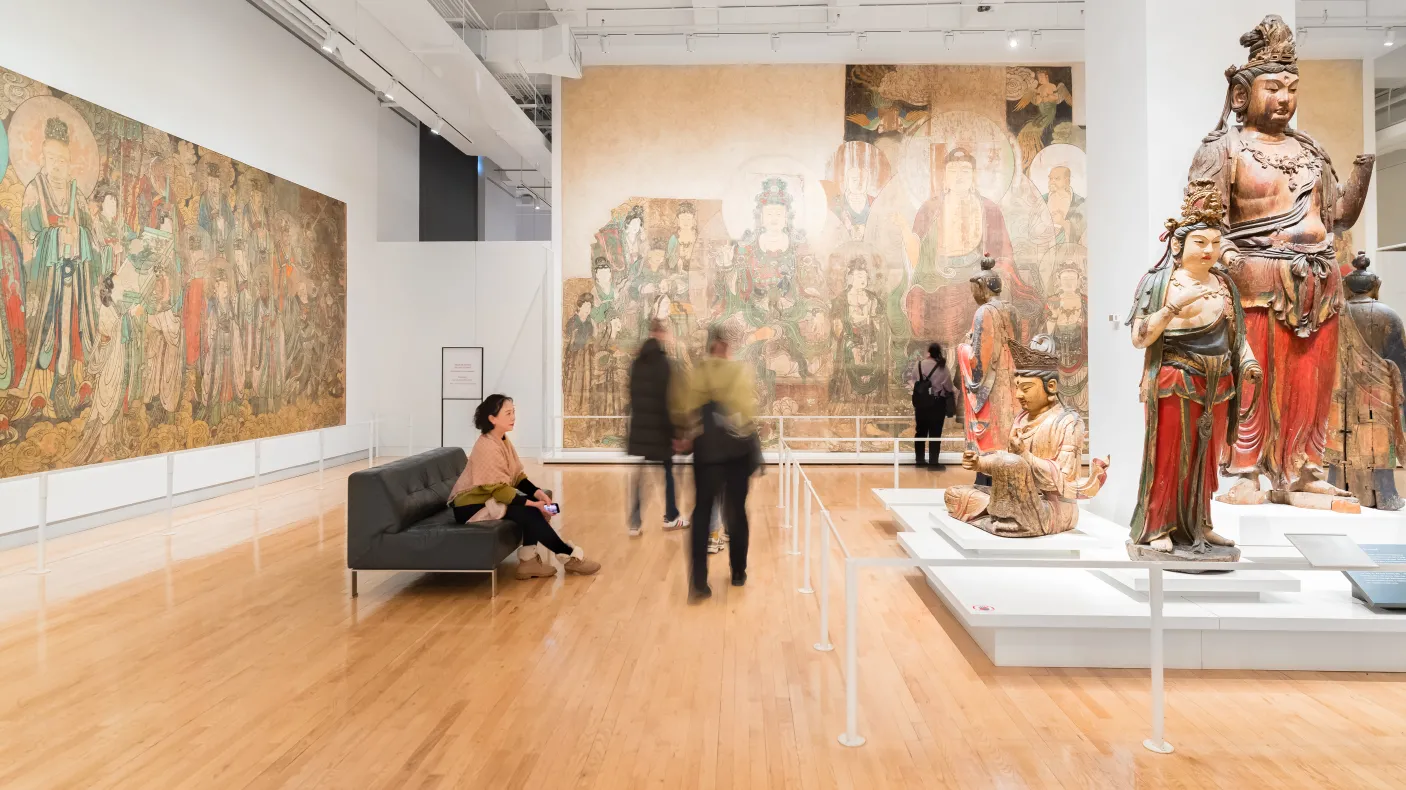 Une femme reste assise et profite d'un moment pour admirer l'art des temples chinois ROMs tandis que d'autres personnes se déplacent autour d'elle.