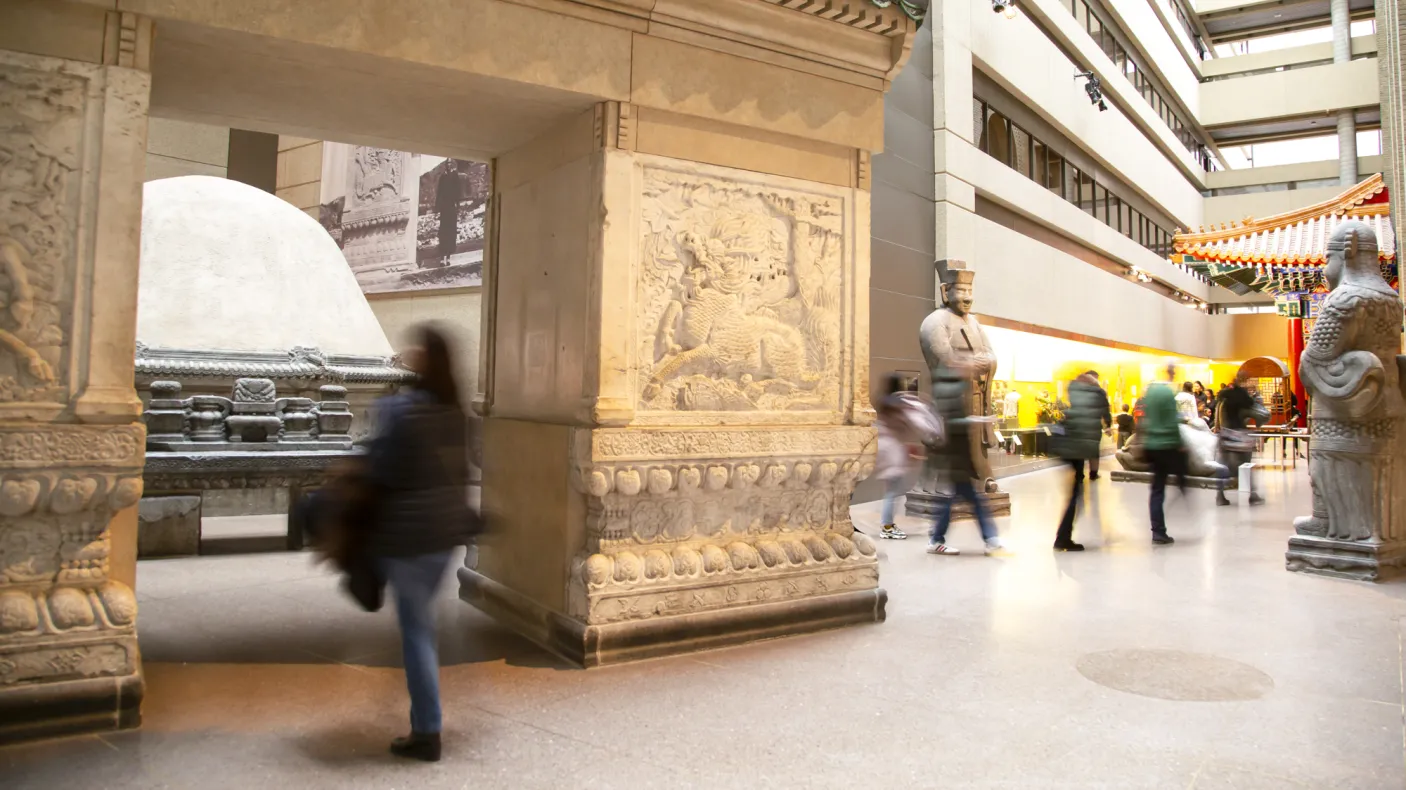 People walk through a gallery with a large entry gate