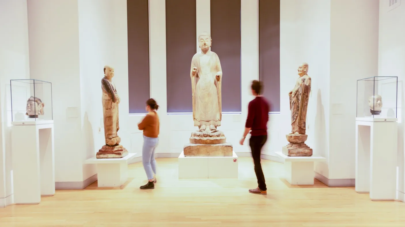 Two people look at three large Chinese sculptures.