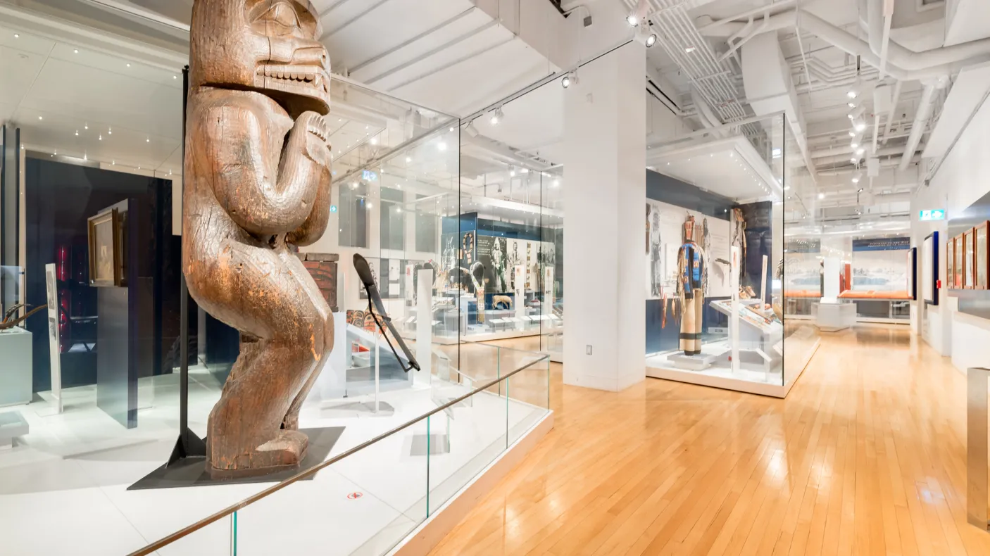 Une galerie avec, au premier plan, un grand poteau de maison en bois sculpté