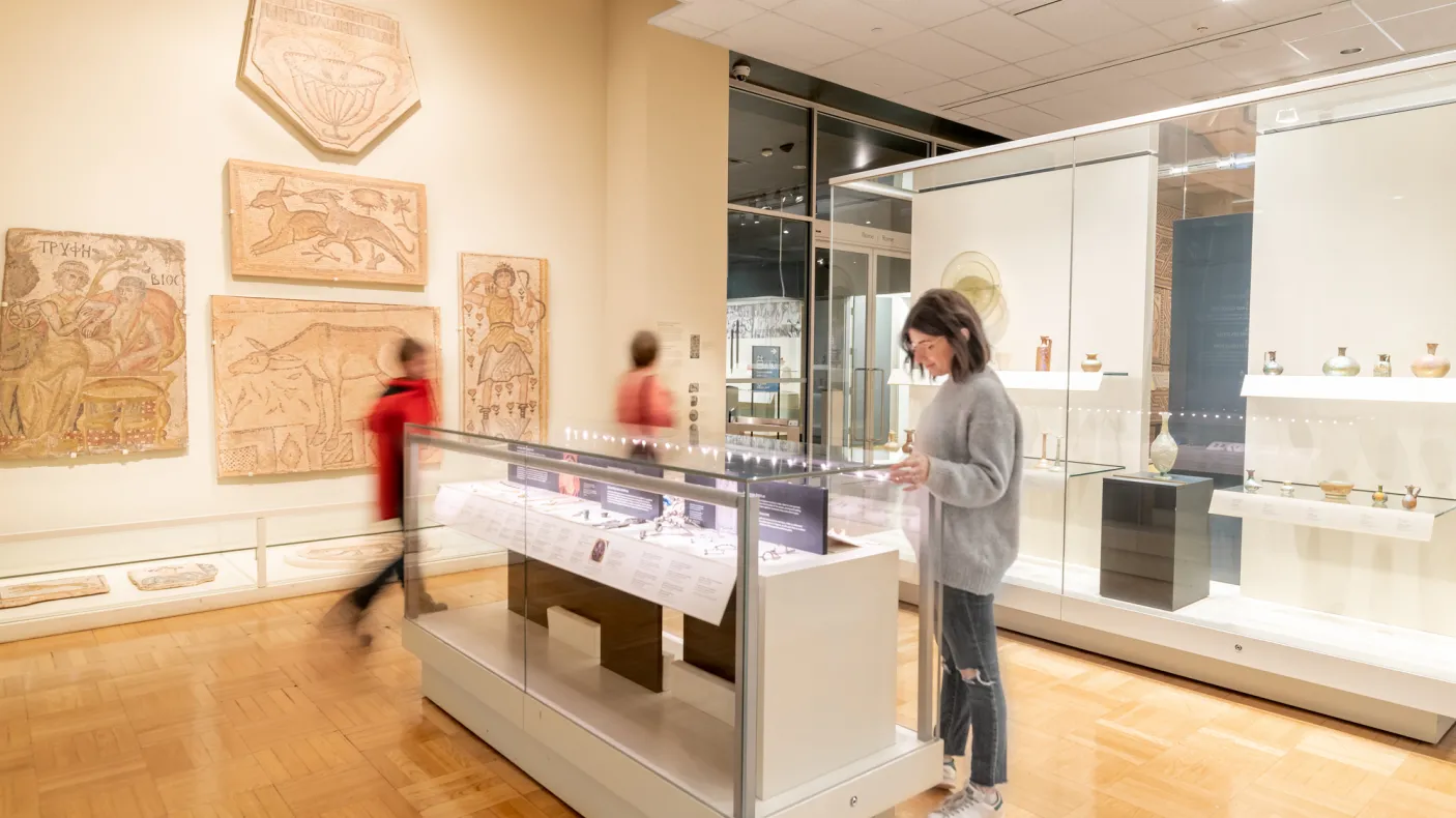 A person pauses to examine an object in a case.