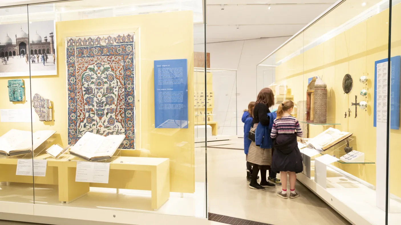 Une famille examine un objet du Moyen-Orient dans la vitrine d'une galerie.