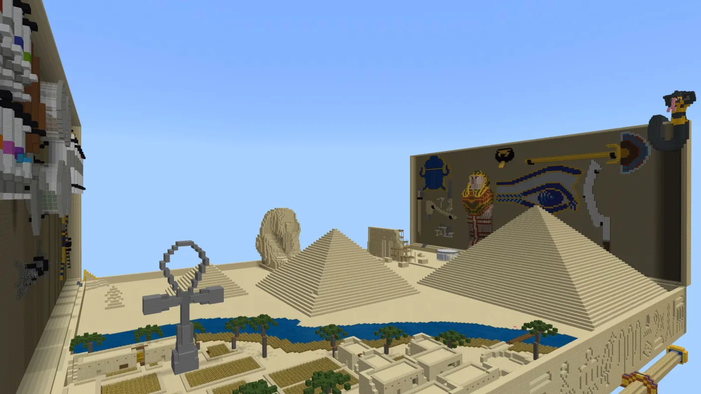 A minecraft screenshot showing a desert crossed by a blue river, pyramids, a giant ankh, and other Egyptian elements