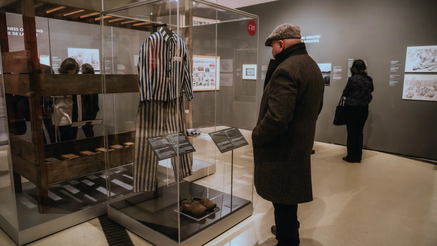 A visitor in the exhibition at ROM looks in at a display case.