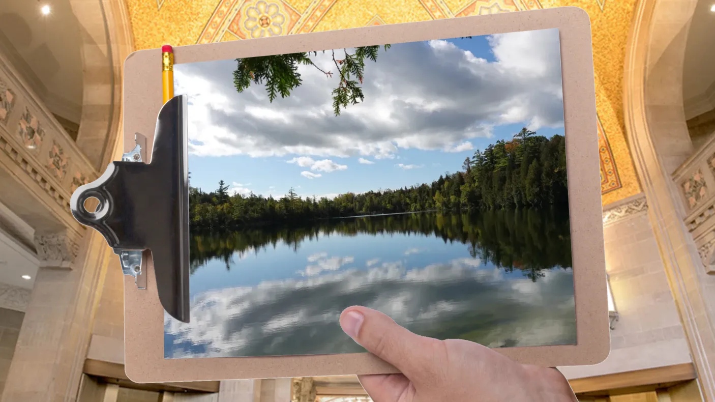 A hand holds a clipboard in front of a gallery at ROM. The clipboard displays an image of a glassy lake ringed by trees