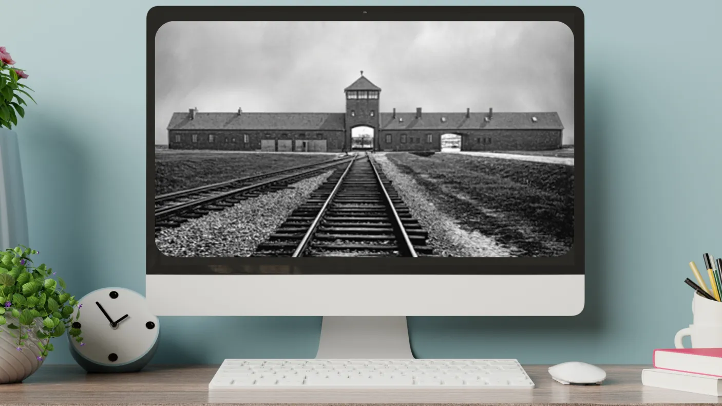 A computer on a desktop shows a black-and-white image railroad tracks leading toward an arched gate beneath a peaked tower.