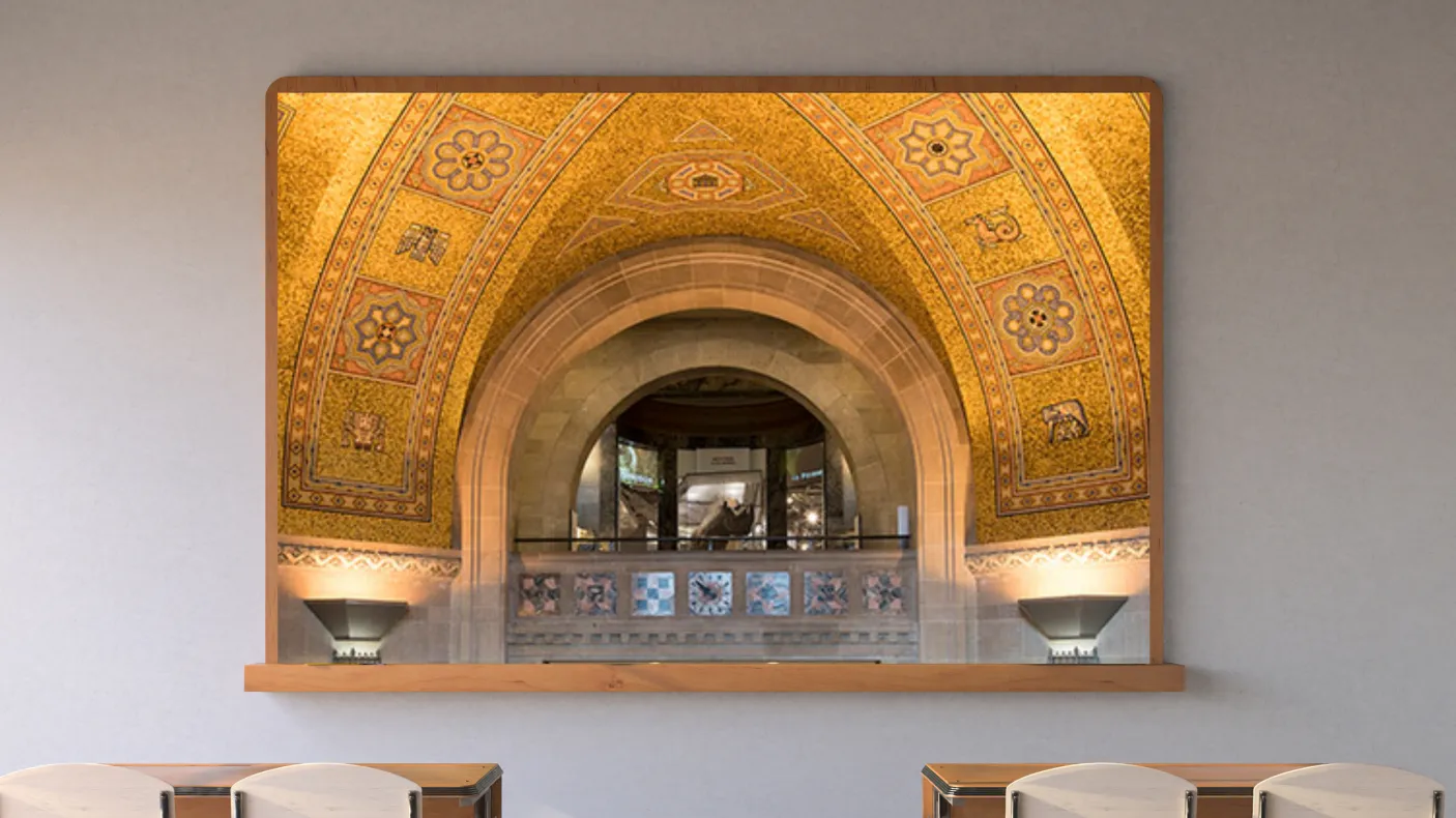 A screen in a classroom displays a balcony with an arched roof beneath a golden mosaic ceiling. A rhinoceros in a case is visible through the arch.