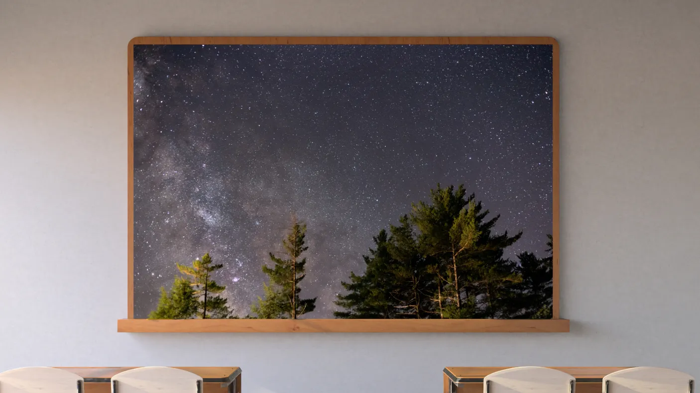 A screen in a classroom displays an image of the starry night sky framed by trees.