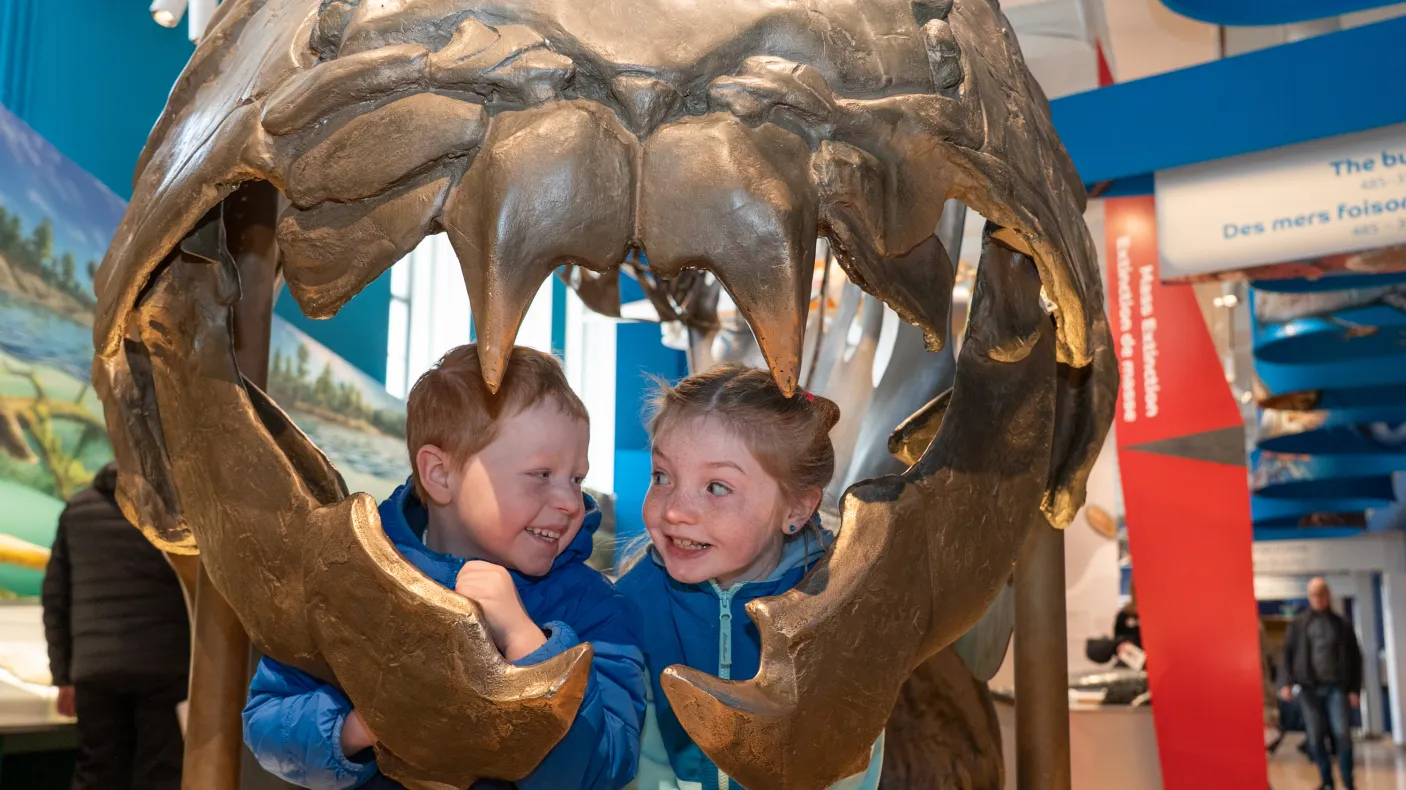 Two children look out from the mouth of the Dunkleosteus in the Dawn of Life Gallery