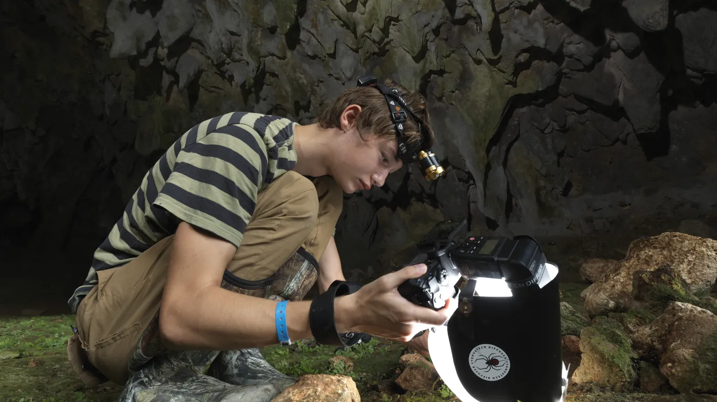 Beckett Robertson, deep inside a cave in the Dominican Republic, where he captured his award-winning photo of a whip spider. (2023)