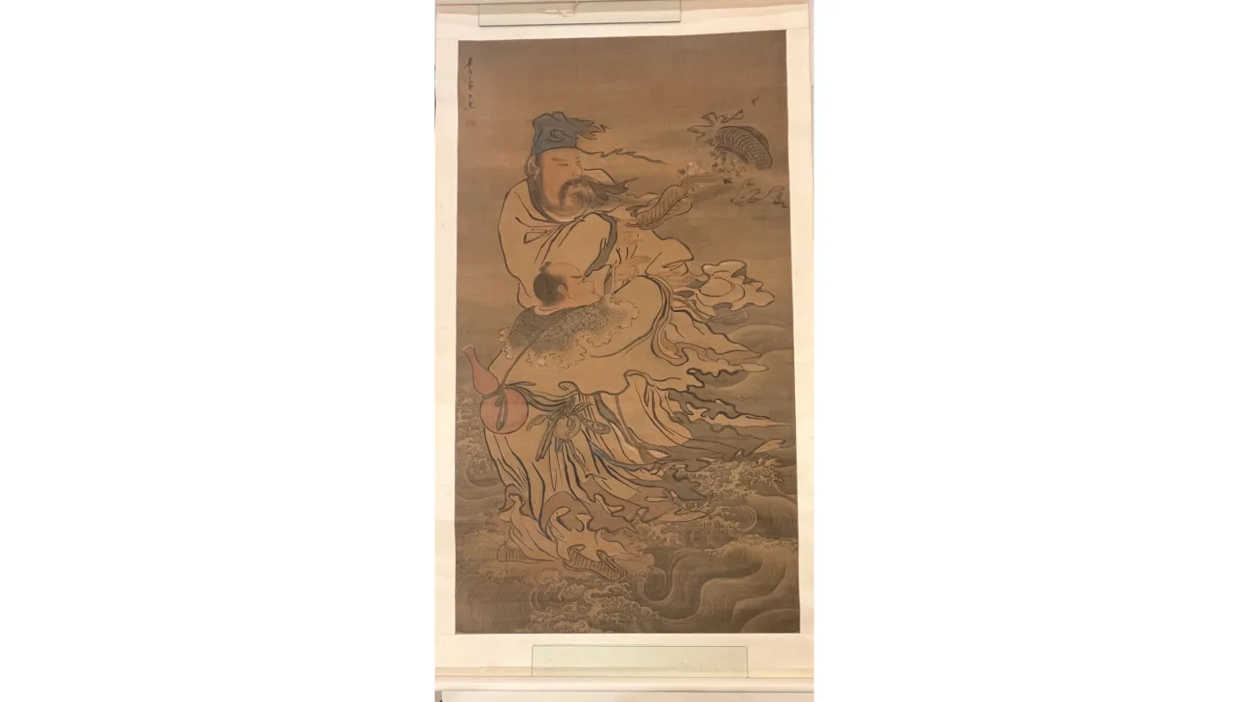 Vertical hanging scroll painting depicting two robed figures amid swirling water and wind. A taller figure stands above, wearing layered robes and a head covering, with long ribbons and sleeves flowing outward. Below, a smaller figure is carried or supported, partially wrapped in the taller figure’s garments. Waves and curving lines fill the lower half of the composition, suggesting movement through water, while fish-like forms and drifting elements appear near the upper right. The artwork is rendered in mu