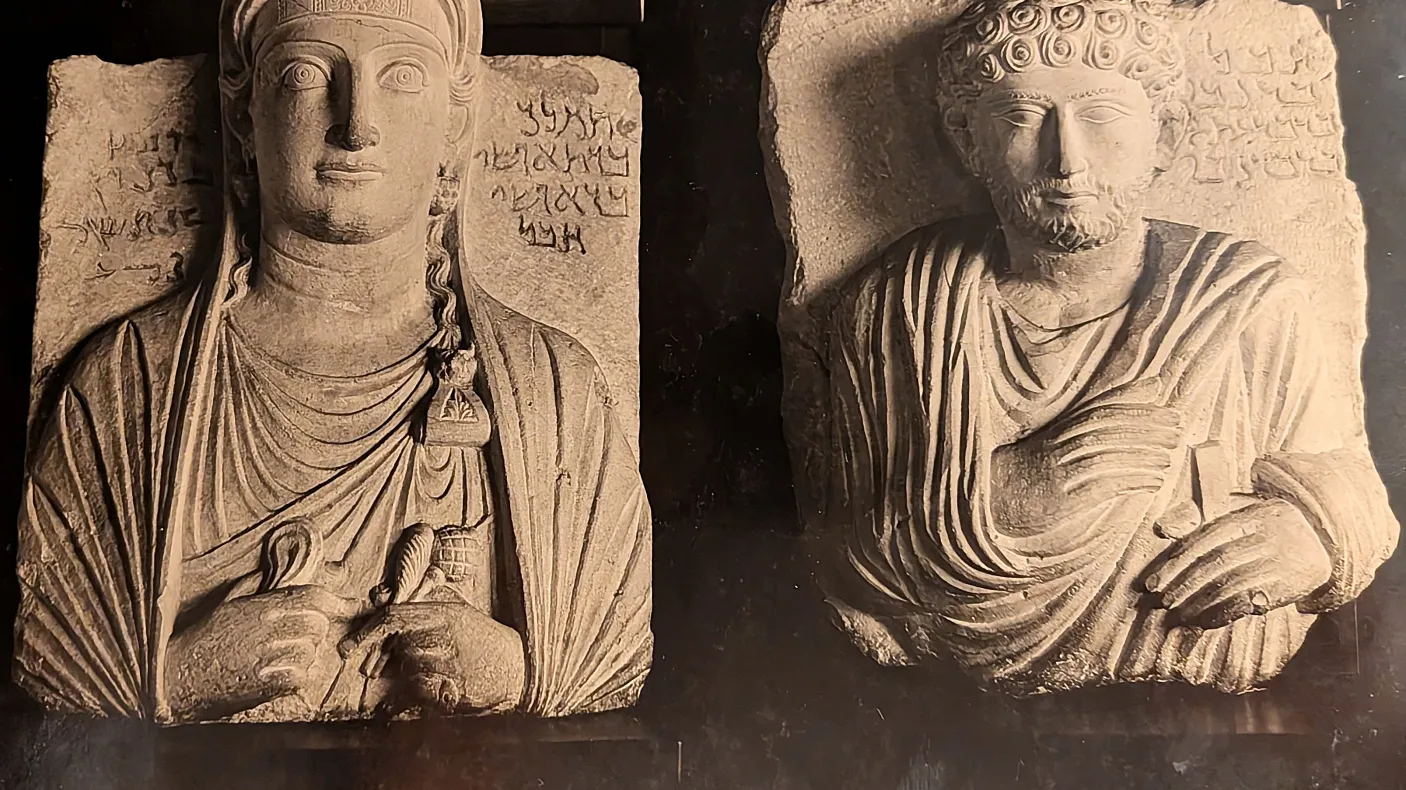 Left: Limestone stele depicting a woman with long hair and rectangular face; right: Limestone stele depicting a man with curly hair and beard, both wearing draped garments and seated.